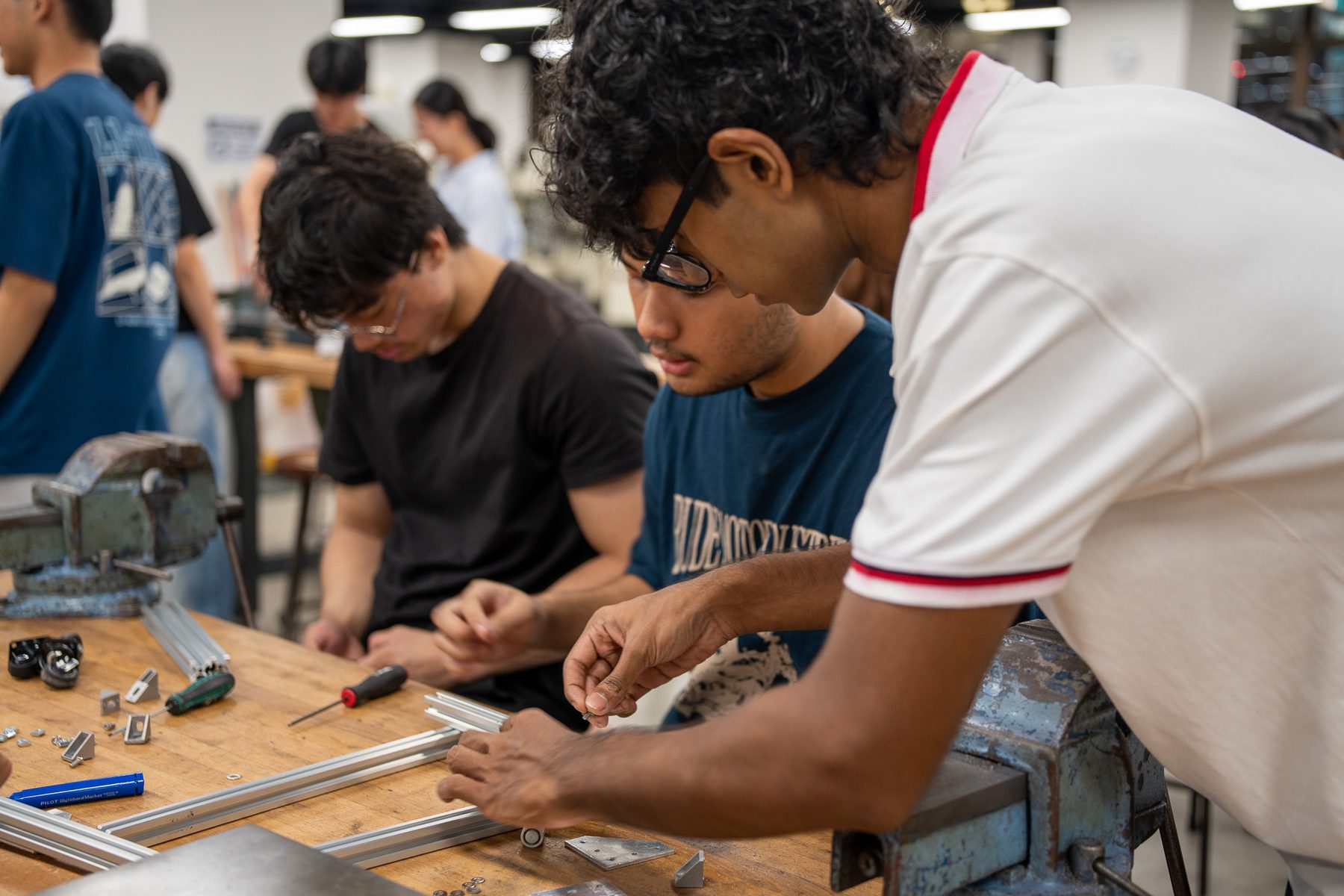 Students assembling an aluminum frame during hands-on robotics training