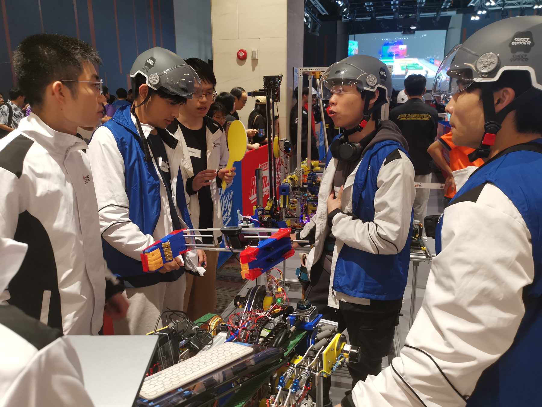 Robocon team members inspecting their robot and discussing field tasks