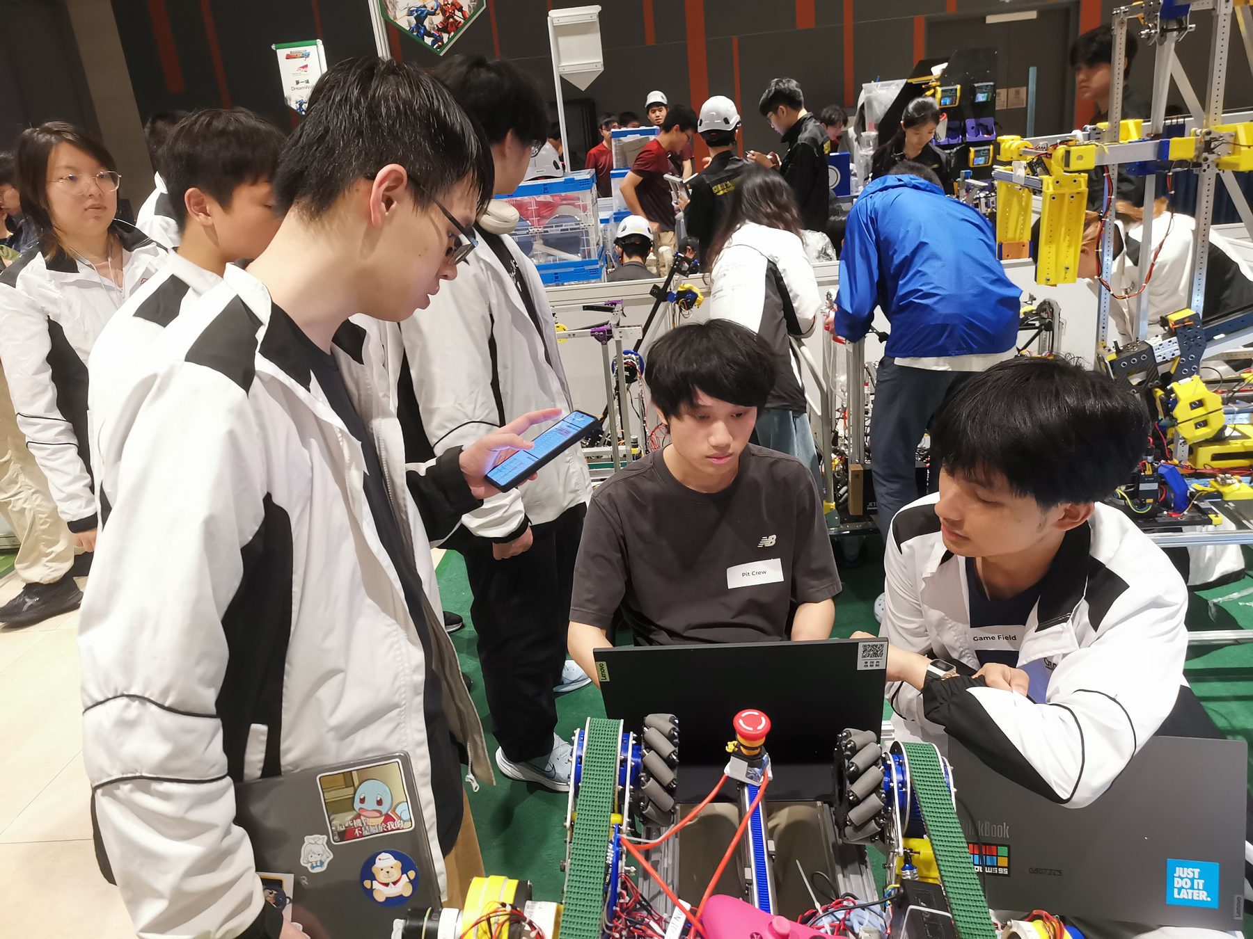 Robocon team members reviewing plans around a robot and laptop