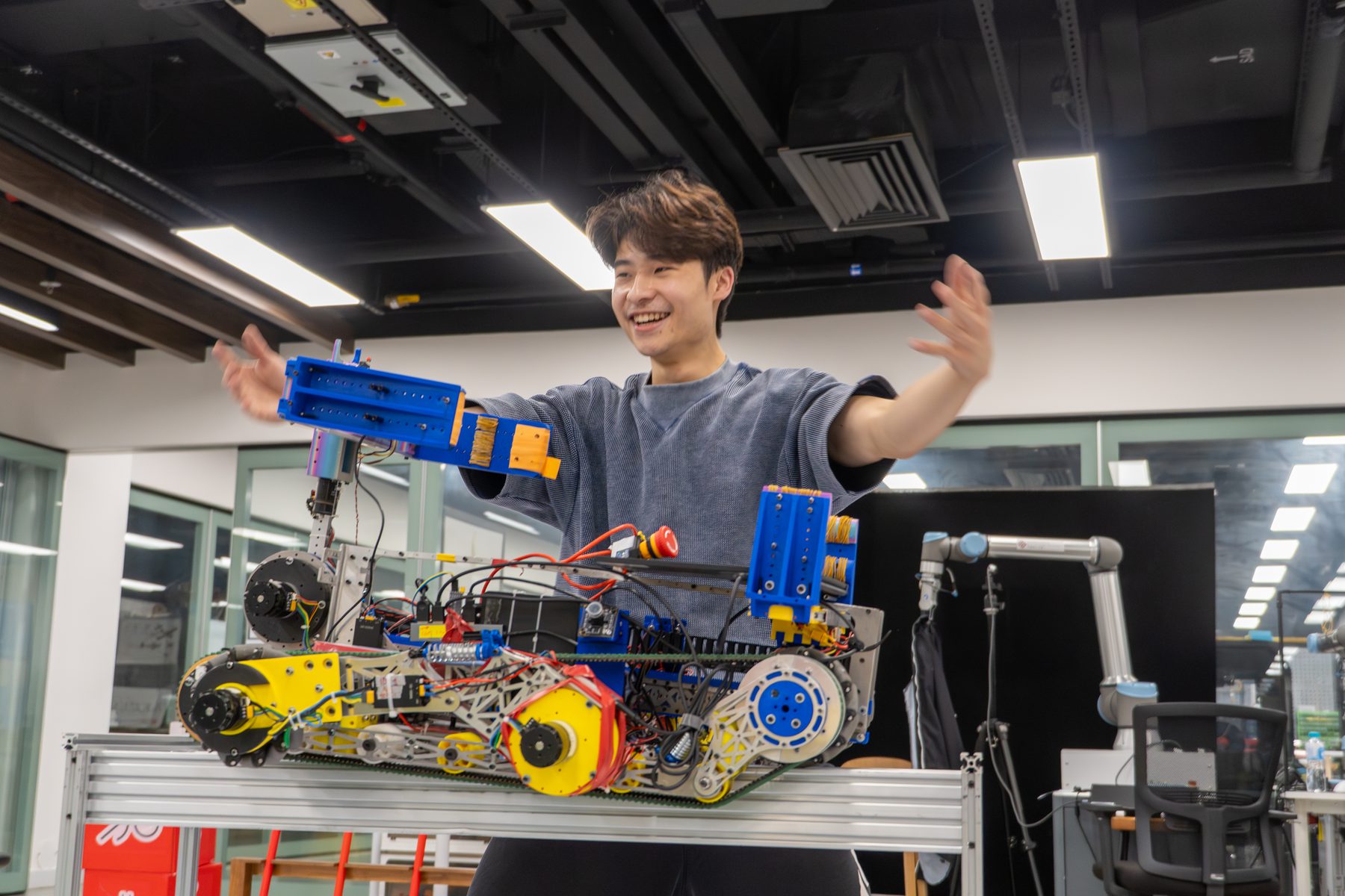 Student demonstrating a large Robocon robot platform in the lab